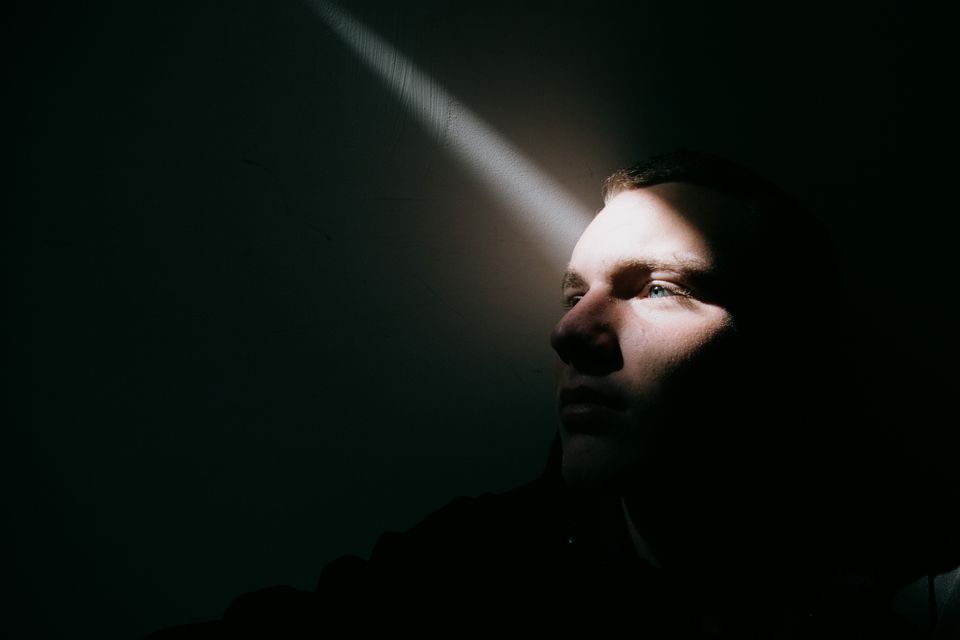Man in darkness with a bit of light on his face representing holding your tongue