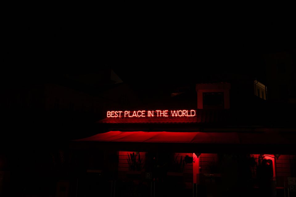 Neon sign saying "best place in the world" representing trapping in coddling