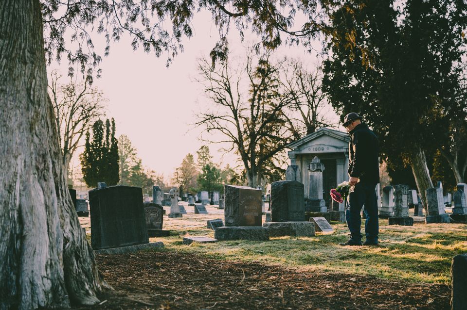 Man at a gravestone representing Herman Cain Award