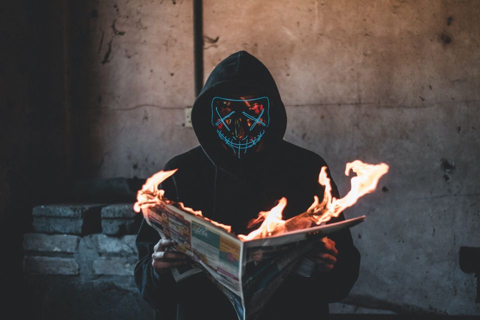 Man reading burning newspaper representing chaos and negativity