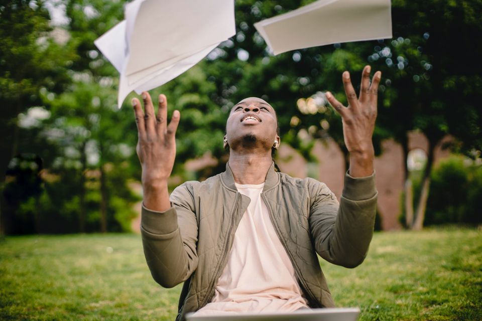 A man tossing up papers being freed from self consciousness