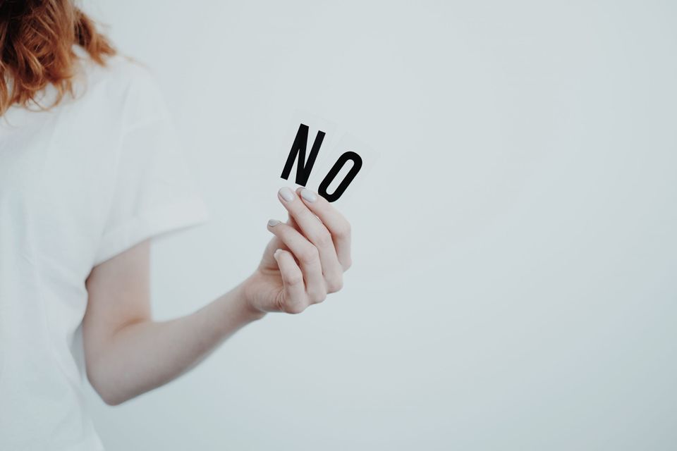 Woman holding the word "No" representing being rejected on purpose