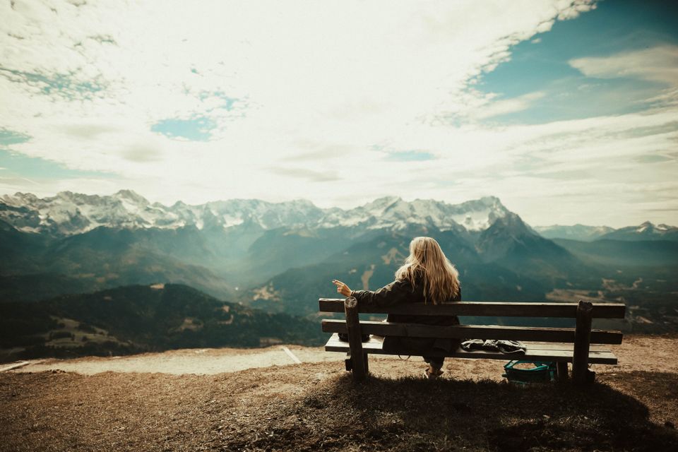 Woman on a bench with bright scenery representing reasons you deserve to be happy